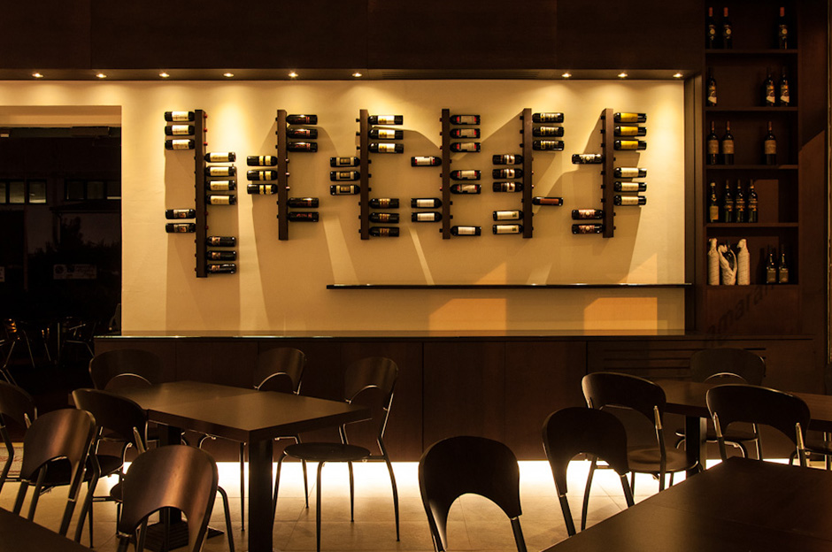 La parete con l\'esposizione di vini ed il banco per aperitivi
